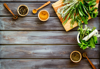 Making spices. Herbs in motar and dry flavorings on dark wooden desk top-down copy space