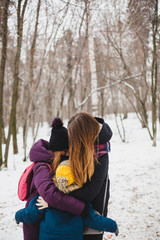 Fototapeta na wymiar Mother hugs her children, daughter and son, sister and brother, family, walk in the winter forest