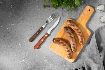 Grilled sausages on a wooden Board on a light gray kitchen table. View top