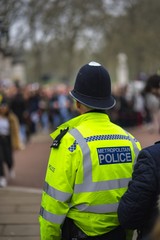 Vertical shot of a police officer in front of the historic Buckingham Palace