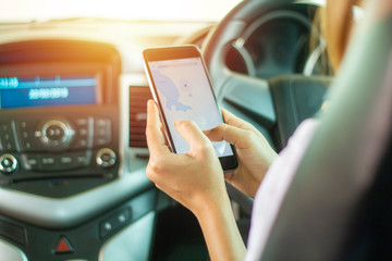 Asian women are driving cars and using a smartphone on the road.