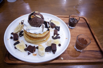 Pancakes with bananas and brownies topped with whipped cream and chocolate ice cream