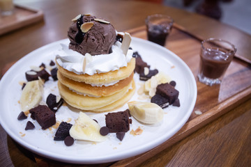 Pancakes with bananas and brownies topped with whipped cream and chocolate ice cream