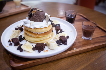 Pancakes with bananas and brownies topped with whipped cream and chocolate ice cream