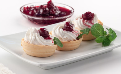 Homemade tartlets with cream cheese, cherry jam and mint