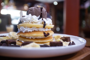 Pancakes with bananas and brownies topped with whipped cream and chocolate ice cream