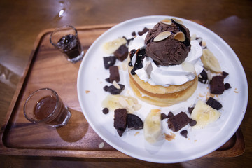 Pancakes with bananas and brownies topped with whipped cream and chocolate ice cream