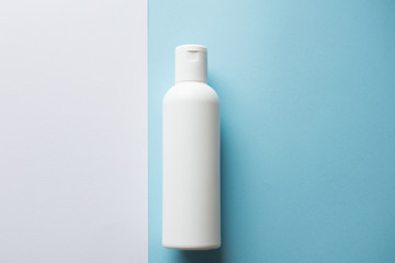 white shampoo bottle on a blue and white background. Copy space