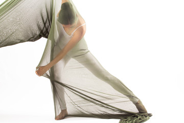 Adult woman dancing in a tube of fabric in studio.