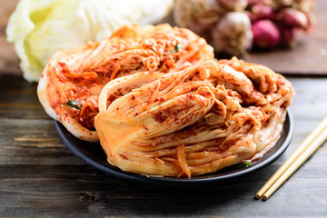 Kimchi cabbage on black plate with chopsticks on wooden background, Korean food