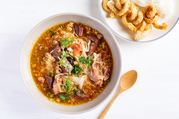 Northern Thai food (Kanom Jeen Nam Ngeaw), rice noodles with spicy soup in a bowl eating with pork rind on white table