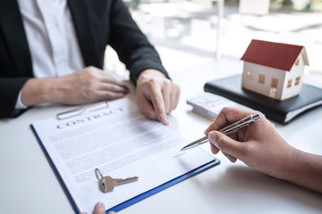 Sale purchase contract to buy a house, Real estate agent are presenting home loan and giving keys to customer after signing contract to buy house with approved property application form
