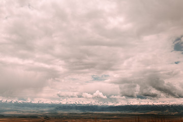 Landscape with mountains, clouds, water, and roads in a Central Asian country