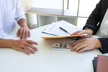 Illegal, dishonest, bribery and corruption concept, Businessman giving bribe money in the envelope of their partner to give success the deal contract in a corruption scam for bribing