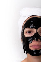 Portrait of a beautiful young woman with a cleansing black mask dripping from her face
