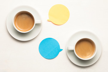 Two cup of coffee on a white wooden table with orange and blue balloons with copy space