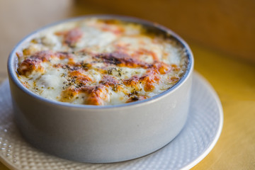 Lasagna with parmesan cheese on wood table in restaurant
