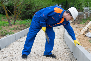 senior worker checks the completion of work on the construction of a pedestrian road