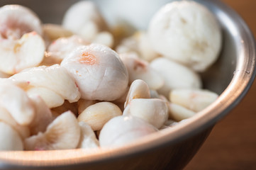 Mangosteen flesh out of its shell in a metal bowl.