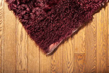 A fragment of the coating (carpet) of natural Burgundy fur on the parquet floor, interior decoration