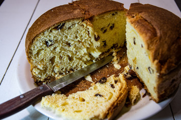 Sliced sweet muffin with raisins on the kitchen table in a white plate and skins.