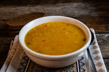 Pea soup in a white ceramic bowl on a kitchen napkin against the background of old wooden boards. Cooking homemade food.