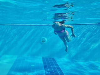 Bodies of girl swimming in a pool under water. Blue