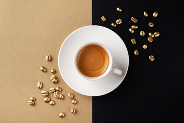 Cup of coffee and coffee beans on gold black background. Creative flat lay. Top view.