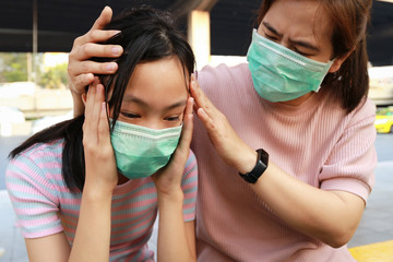 Tired asian child girl crying with hygienic mask suffer from headache and air pollution,allergy to...