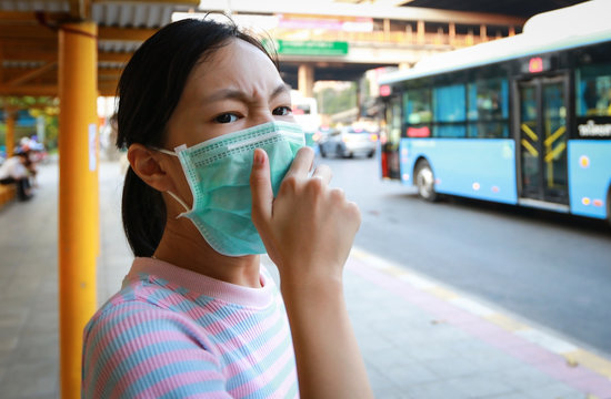 Tired Asian Child Girl Cough Wearing Hygienic Mask,stressed Worried About Air Pollution Problems,toxic Fumes,PM 2.5,dust,bad Environment At Bus Stop In City,protect Their Health From Pollution Smog