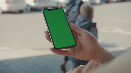 NEW YORK - May 19, 2019: Young hands woman holding use vertical phone with green screen typing scrolling pages swiping surfing internet technology smartphone chroma key message mobile phone slow