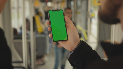 NEW YORK - May 19, 2019: Slow motion man young hand uses holding a mobile telephone with a vertical green screen background tram inside window key smartphone technology touch message display close up
