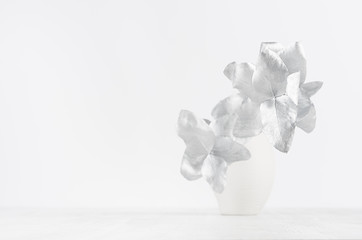 Gentle white home decor with ceramic vase with decorative silver bouquet for christmas on white wood table, copy space.