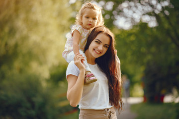 Obraz premium Family sitting in a summer park. Mother in a white t-shirt. Cute little girl