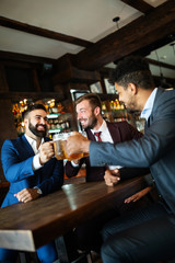 Meeting with the best friends. Happy young business men talking and drinking beer in a pub