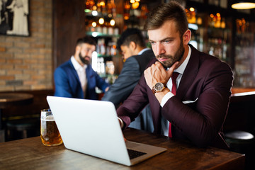 Portrait of a successful business man sitting at the cafe working on a laptop.
