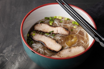 Composition with a bowl of rice noodles, meat and vegetables