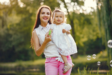 Family sitting in a summer park. Mother in a white t-shirt. Cute little girl