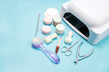 Set of cosmetic tools for manicure and pedicure on on a light blue background. Gel polishes, nail files and nippers and a lamp top view. Copy space. 