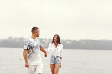 Cute couple walking near water. Girl in a white shirt. Pair by the river
