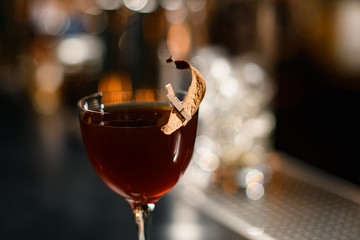 Delicious brown cocktail in the glass decorated with a dried leaf by a pin