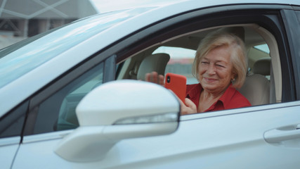 Portrait senior woman sits in car use red cell phone smile happy businesswoman blonde people smartphone cellphone communication internet search lady mobile bench browse network online slow motion