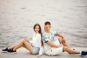 Cute couple sitting near water. Girl in a white shirt. Pair by the river