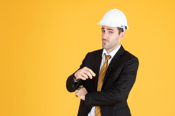 Young handsome businessman wears suit and construction helmet on isolated yellow background.