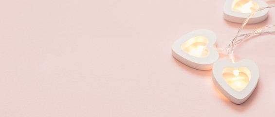 Minimal Valentine's Day or wedding party decoration. Heart shape garland on pink pastel banner. Love concept