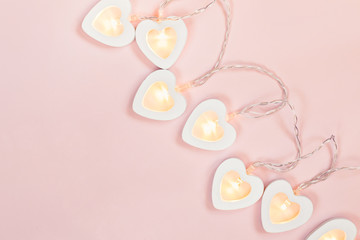 Heart shape garland on pink pastel background. Valentine's Day or wedding party decoration. Love concept