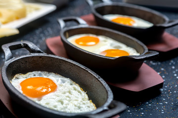 Fried eggs in portions in cast iron dishes