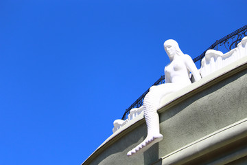 Plaster statue of a mermaid. Woman fish. A symbol found in the folklore of all peoples of antiquity and the Middle Ages. Background with copy space for inscription or text.
