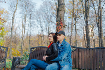 Happy lovers in the park on a bench in autumn.