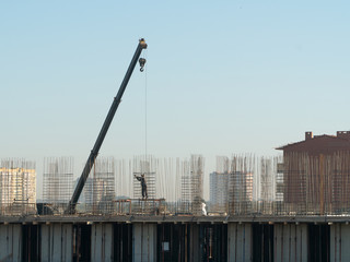 Construction of a multistorey monolithic residential complex, with workers. A mounting crane...